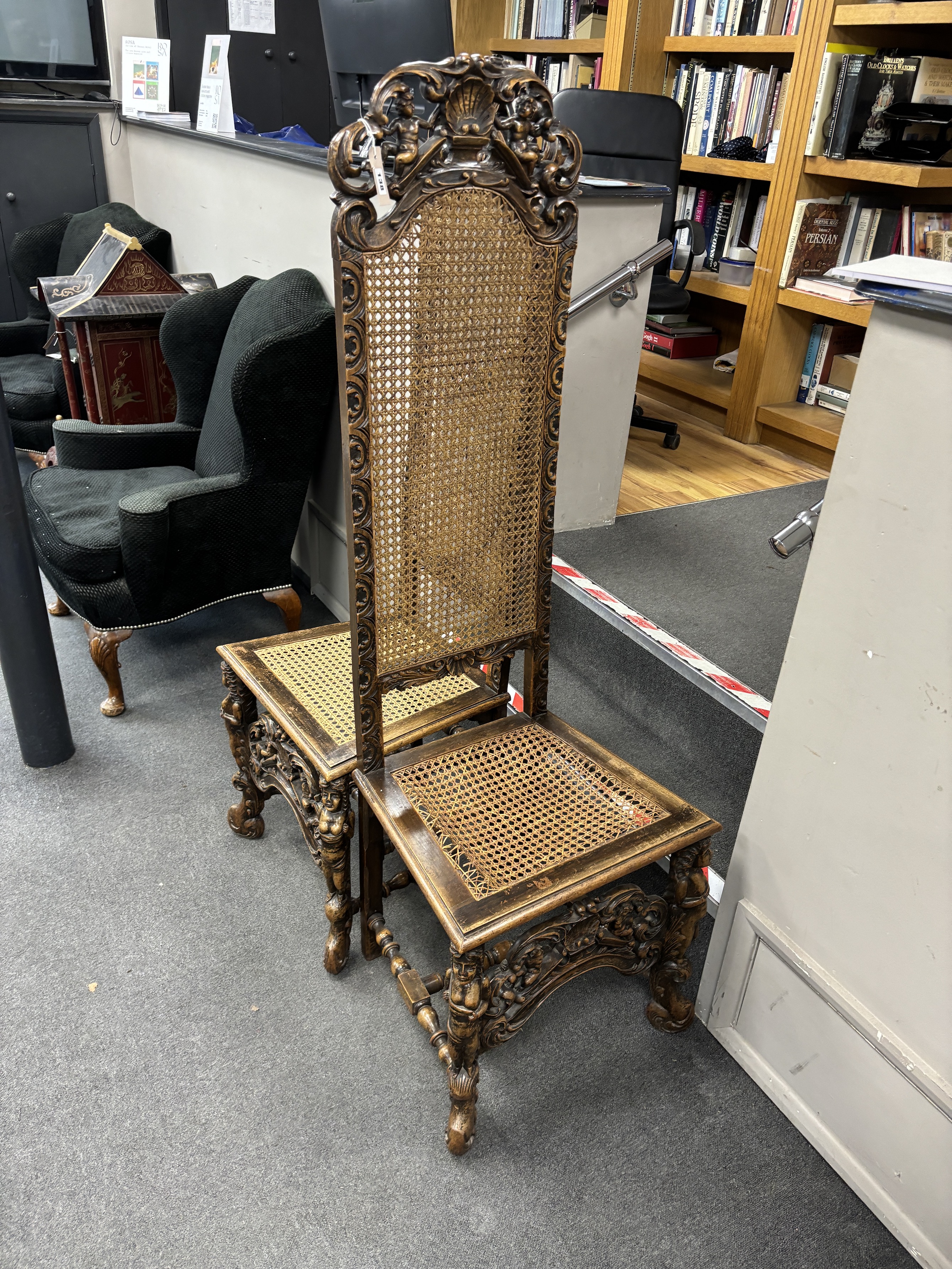 A pair of Cromwellian style carved beech and walnut caned high back hall chairs, height 159cm.